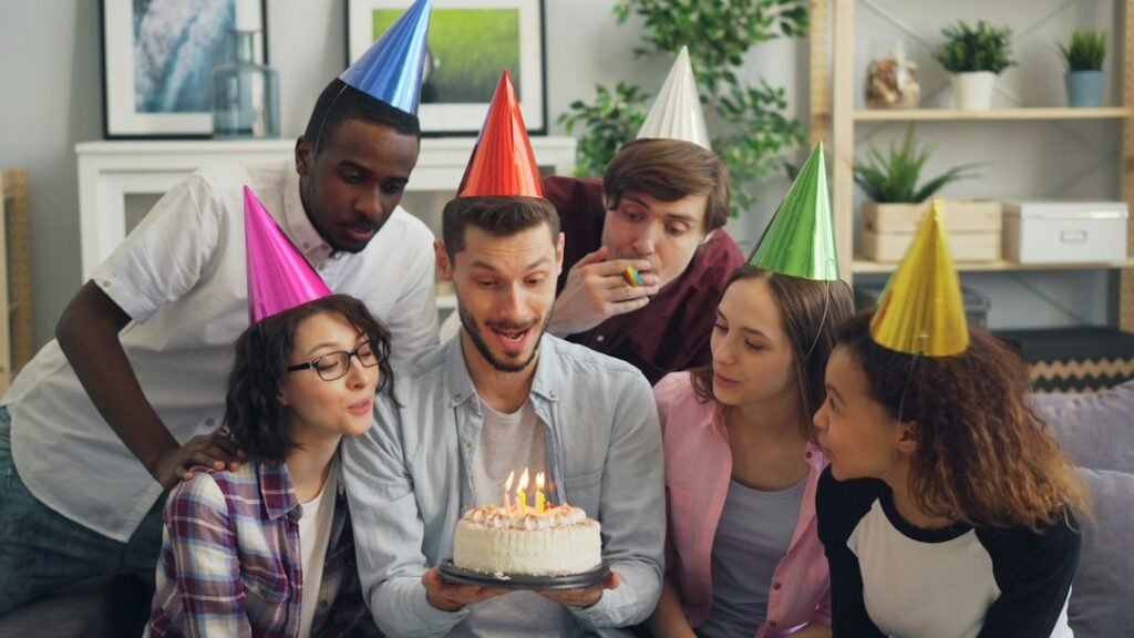 Friends celebrating a birthday around a cake with candles